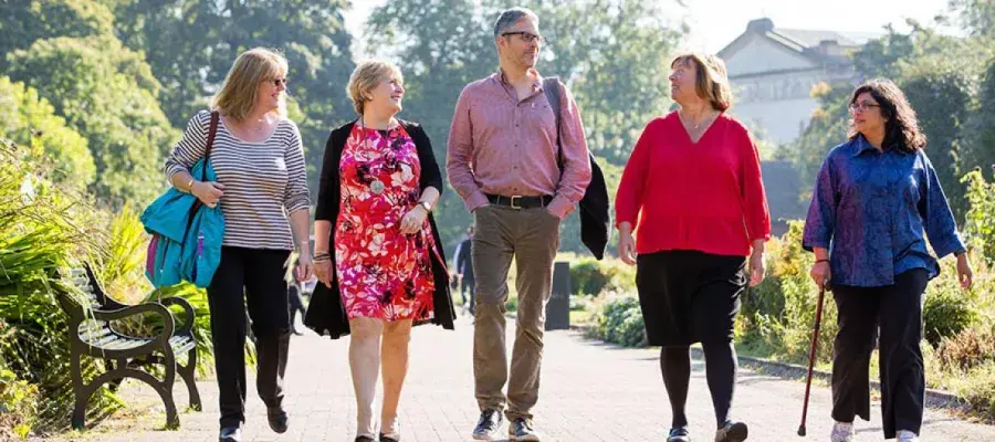 A group of five people walking in sunlight