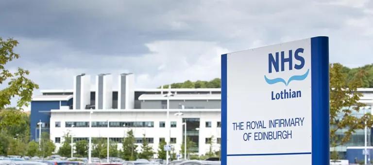 NHS sign with hospital buildings in distance